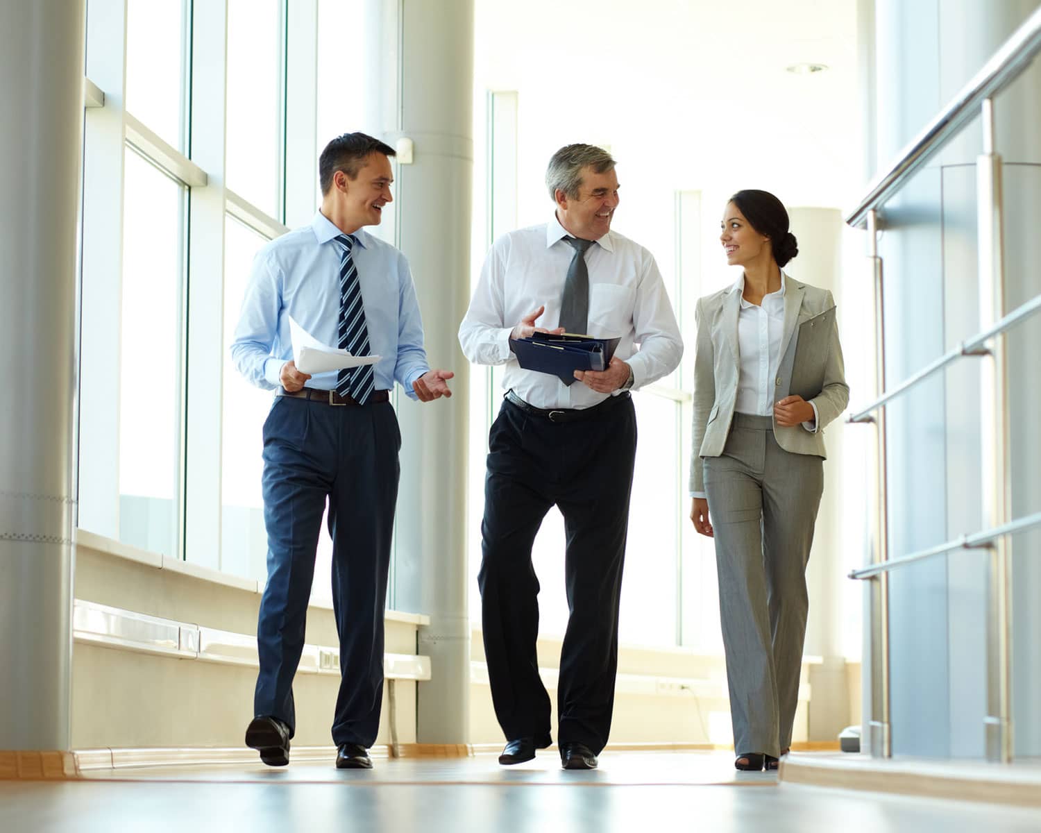 Confident business partners walking down in office building and discussing work