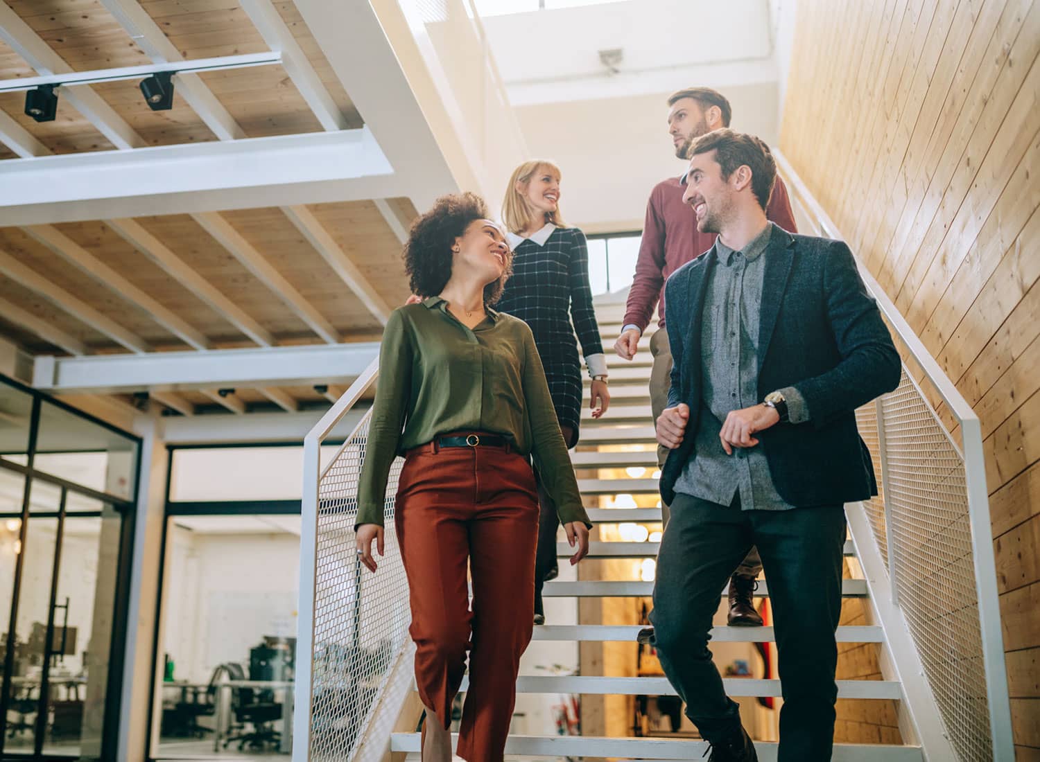 Group of diverse coworkers walking down the stairs in an office.